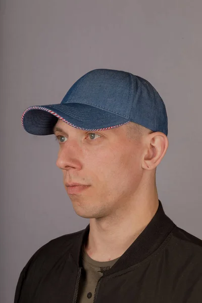 Schöner junger Mann mit Kopfbedeckung auf grauem Hintergrund. — Stockfoto