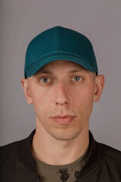 Όμορφος νέος άντρας σε ένα καπέλο σε γκρίζο φόντο. — Φωτογραφία Αρχείου