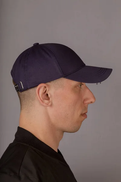 Joven guapo con un tocado sobre un fondo gris . — Foto de Stock