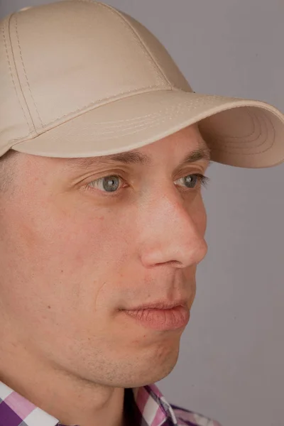 Όμορφος νέος άντρας σε ένα καπέλο σε γκρίζο φόντο. — Φωτογραφία Αρχείου