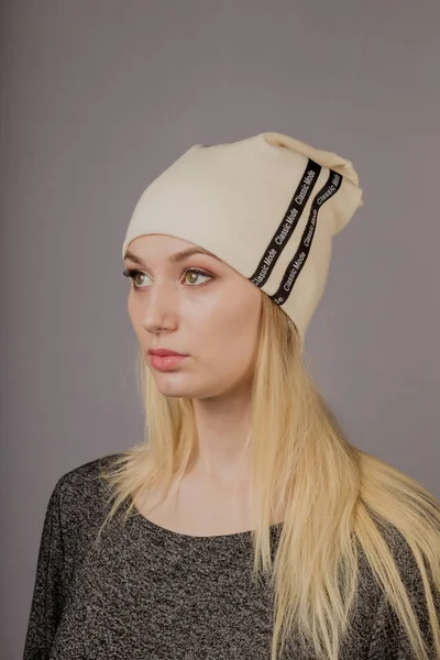 Retrato de una hermosa joven en un elegante tocado con maquillaje natural sobre un fondo gris . — Foto de Stock