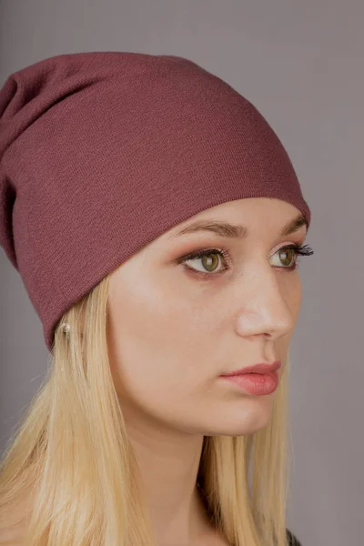 Retrato de una hermosa joven en un elegante tocado con maquillaje natural sobre un fondo gris . — Foto de Stock