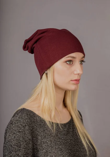 Retrato de una hermosa joven en un elegante tocado con maquillaje natural sobre un fondo gris . — Foto de Stock