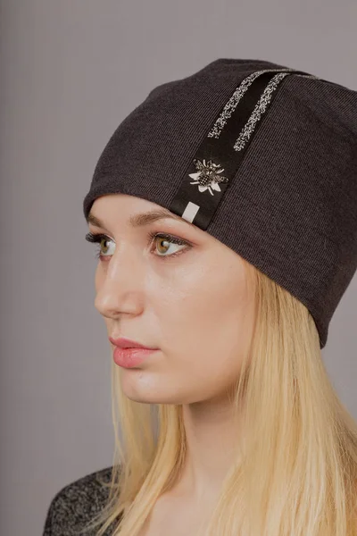 Portrait of a beautiful young girl in a stylish headdress with natural makeup on a gray background. — Stock Photo, Image