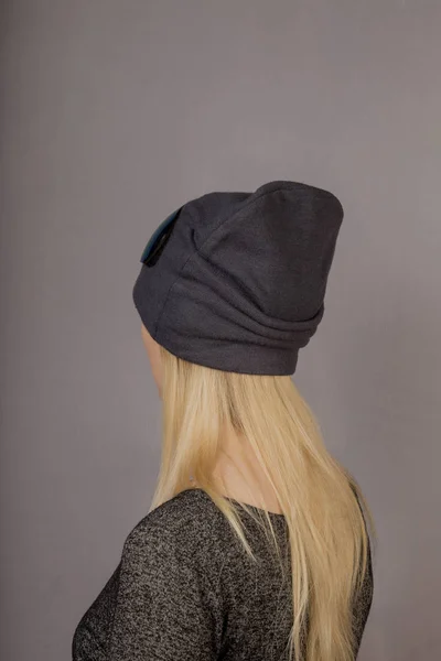 Retrato de una hermosa joven en un elegante tocado con maquillaje natural sobre un fondo gris . — Foto de Stock