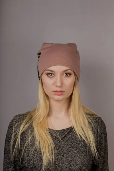 Portrait of a beautiful young girl in a stylish headdress with natural makeup on a gray background. — Stock Photo, Image