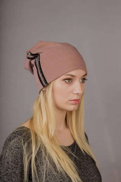 Retrato de una hermosa joven en un elegante tocado con maquillaje natural sobre un fondo gris . — Foto de Stock