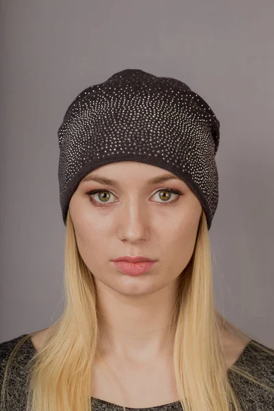 Portrait of a beautiful young girl in a stylish headdress with natural makeup on a gray background. — Stock Photo, Image