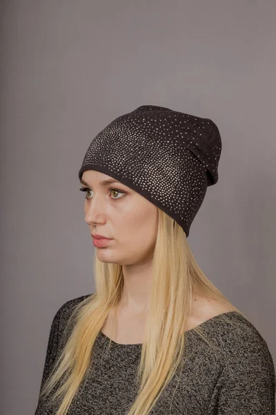 Retrato de una hermosa joven en un elegante tocado con maquillaje natural sobre un fondo gris . —  Fotos de Stock