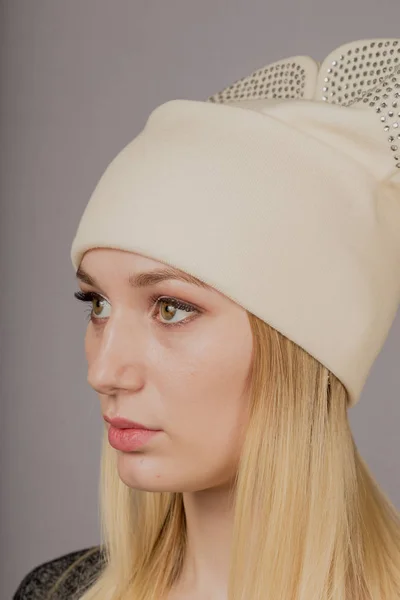 Retrato de una hermosa joven en un elegante tocado con maquillaje natural sobre un fondo gris . — Foto de Stock