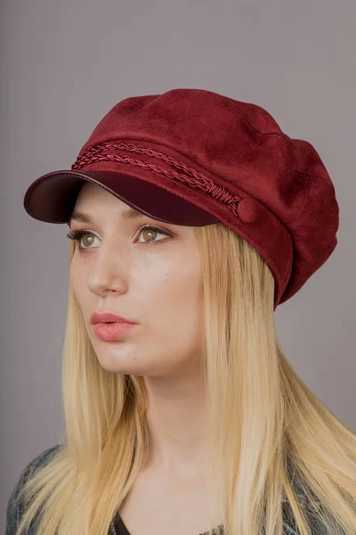 Retrato de una hermosa joven en un elegante tocado con maquillaje natural sobre un fondo gris . —  Fotos de Stock