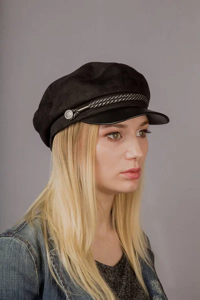 Portret van een mooi jong meisje in een stijlvolle hoofdtooi met natuurlijke make-up op een grijze achtergrond. — Stockfoto