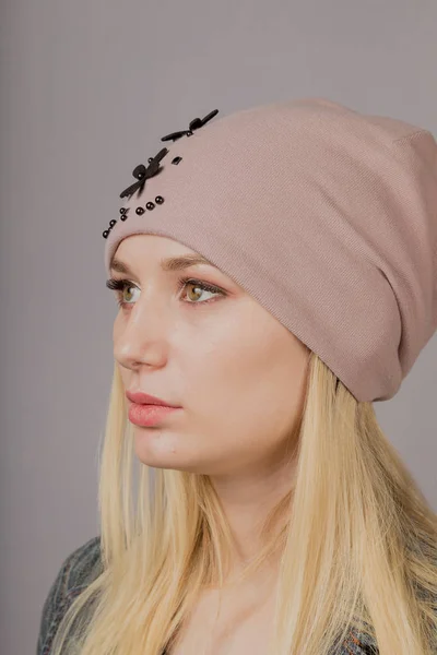 Retrato de una hermosa joven en un elegante tocado con maquillaje natural sobre un fondo gris . — Foto de Stock