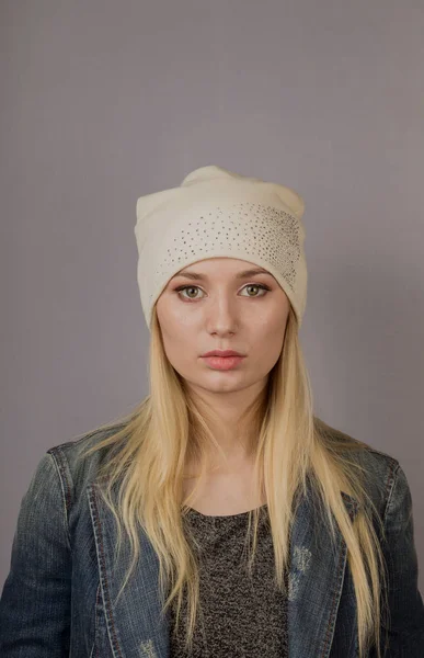 Porträtt av en vacker ung flicka i en snygg huvudbonad med naturlig makeup på en grå bakgrund. — Stockfoto