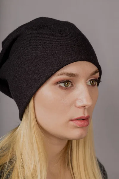 Retrato de una hermosa joven en un elegante tocado con maquillaje natural sobre un fondo gris . — Foto de Stock