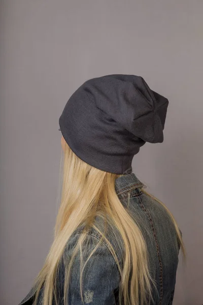 Retrato de una hermosa joven en un elegante tocado con maquillaje natural sobre un fondo gris . —  Fotos de Stock