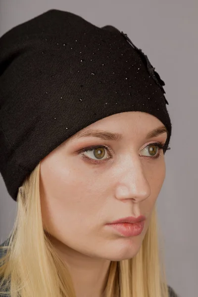 Portrait of a beautiful young girl in a stylish headdress with natural makeup on a gray background. — Stock Photo, Image