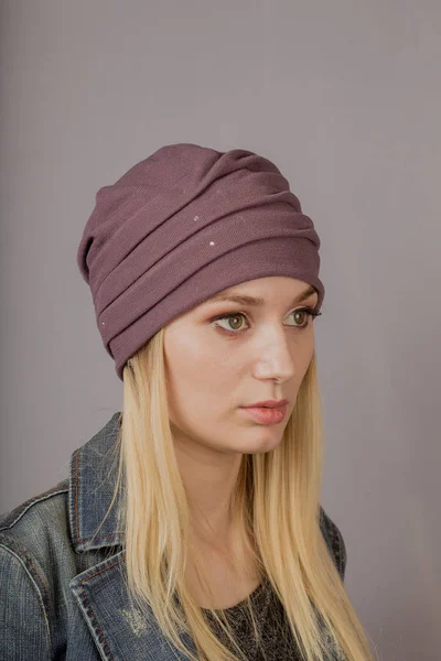 Retrato de una hermosa joven en un elegante tocado con maquillaje natural sobre un fondo gris . — Foto de Stock