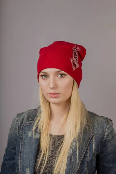 Portret van een mooi jong meisje in een stijlvolle hoofdtooi met natuurlijke make-up op een grijze achtergrond. — Stockfoto