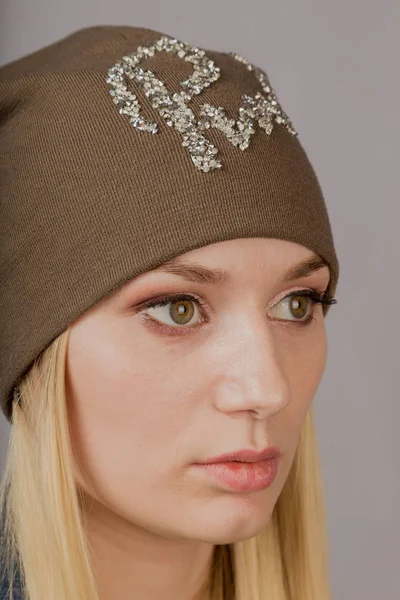 Porträt eines schönen jungen Mädchens in einem stilvollen Kopfschmuck mit natürlichem Make-up auf grauem Hintergrund. — Stockfoto