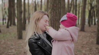 Parkta kollarında bir kız tutan güzel anne.