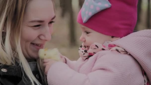 Hermosa madre sosteniendo a una niña en sus brazos en el parque . — Vídeos de Stock