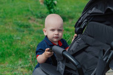 Sıcak yaz aylarında bebek arabasının yanında duran küçük bir çocuk.