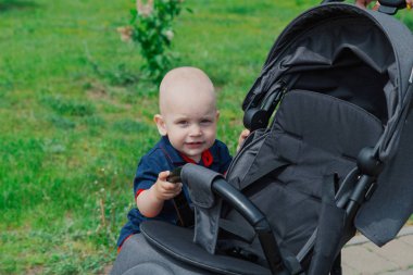 Sıcak yaz aylarında bebek arabasının yanında duran küçük bir çocuk.