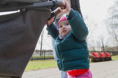 Genç anne bebek arabasında bir bebekle yürüyor..