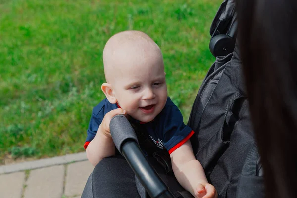 Маленький ребенок, стоящий у детской коляски в теплое летнее время . — стоковое фото