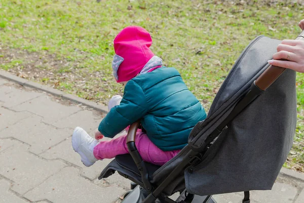 Маленькая девочка сидит в детской коляске на улице — стоковое фото