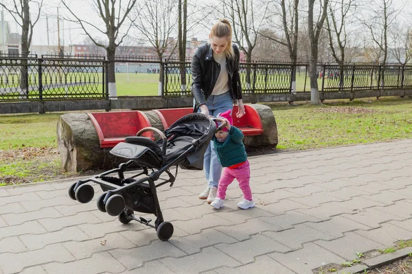 Jonge moeder loopt met een baby in een kinderwagen. — Stockfoto