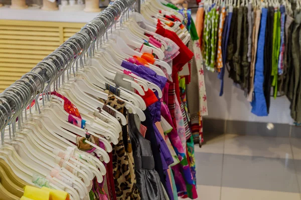 Bellissimi vestiti colorati in un negozio su appendini . — Foto Stock
