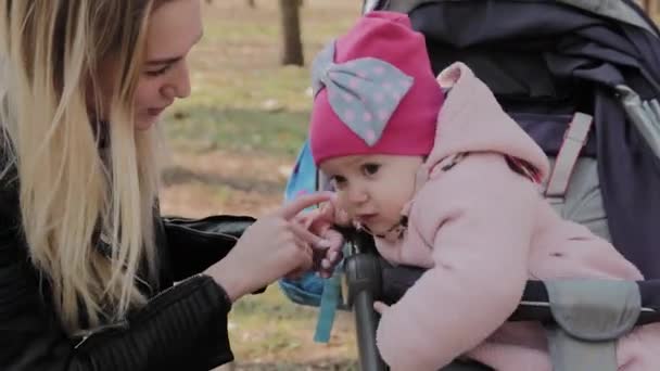 Genç bir anne ve kızı bebek arabasında iletişim kuruyor.. — Stok video