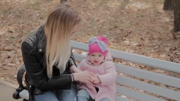 Glückliche Mutter mit kleiner Tochter auf einer Bank im Park. — Stockvideo
