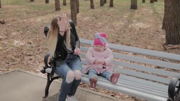 Glückliche Mutter mit kleiner Tochter auf einer Bank im Park. — Stockvideo