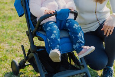 Young mother with a baby in a stroller in a summer park.