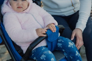 Bebek arabası yla genç bir anne güneşli bir günde bankta oturur..