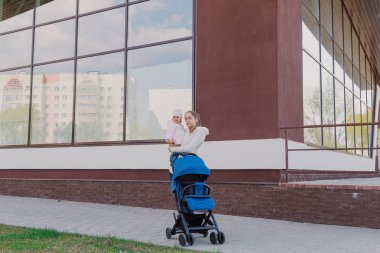 Annelerin elinde küçük bir bebek onlara yakın bir bebek arabası.