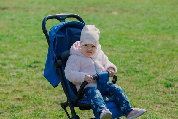 Kis szép lány ül a babakocsi. — Stock Fotó