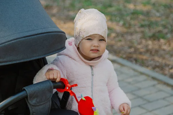 Egy kislány baba gurul a parkban. Gyermek a parkban játszó babakocsi. — Stock Fotó