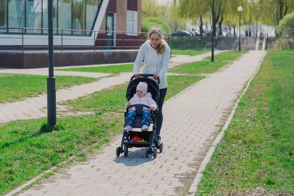 Молодая мать с ребенком в коляске в летнем парке . — стоковое фото