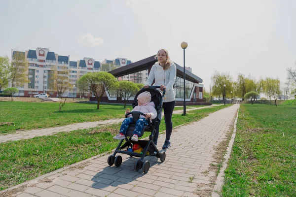 Молодая мать с ребенком в коляске в летнем парке . — стоковое фото