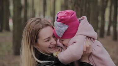 Parkta kollarında bir kız tutan güzel anne.