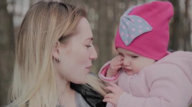 Parkta kollarında bir kız tutan güzel anne.