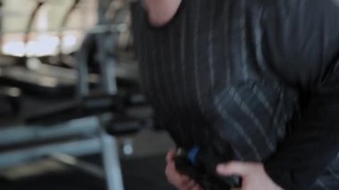Kilolu yetişkin bir adam bir spor salonunda hiperuzantısı gerçekleştirir.