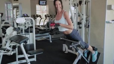Genç güzel kadın spor salonunda hiperuzantısı gerçekleştirir.