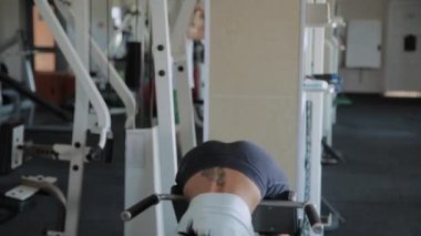 Genç güzel kadın spor salonunda hiperuzantısı gerçekleştirir.