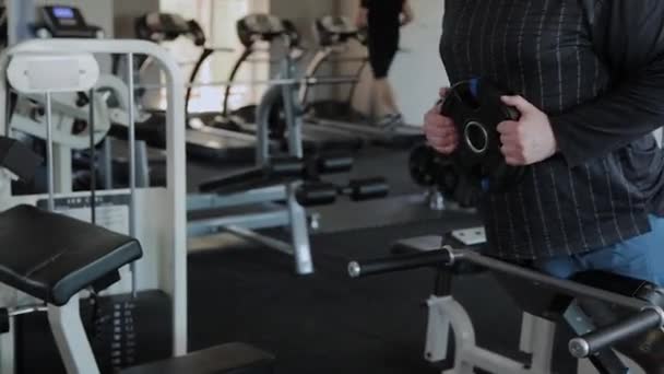 En övervikt vuxen man utför översträckning i ett gym. — Stockvideo