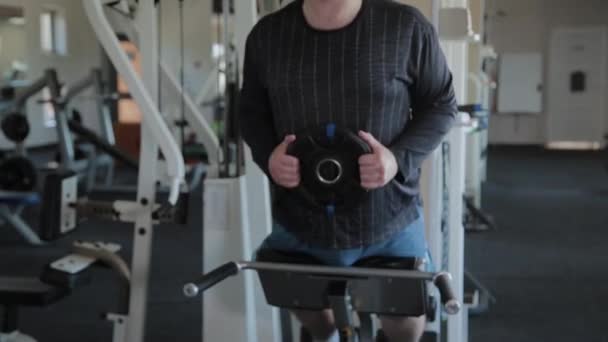 En övervikt vuxen man utför översträckning i ett gym. — Stockvideo